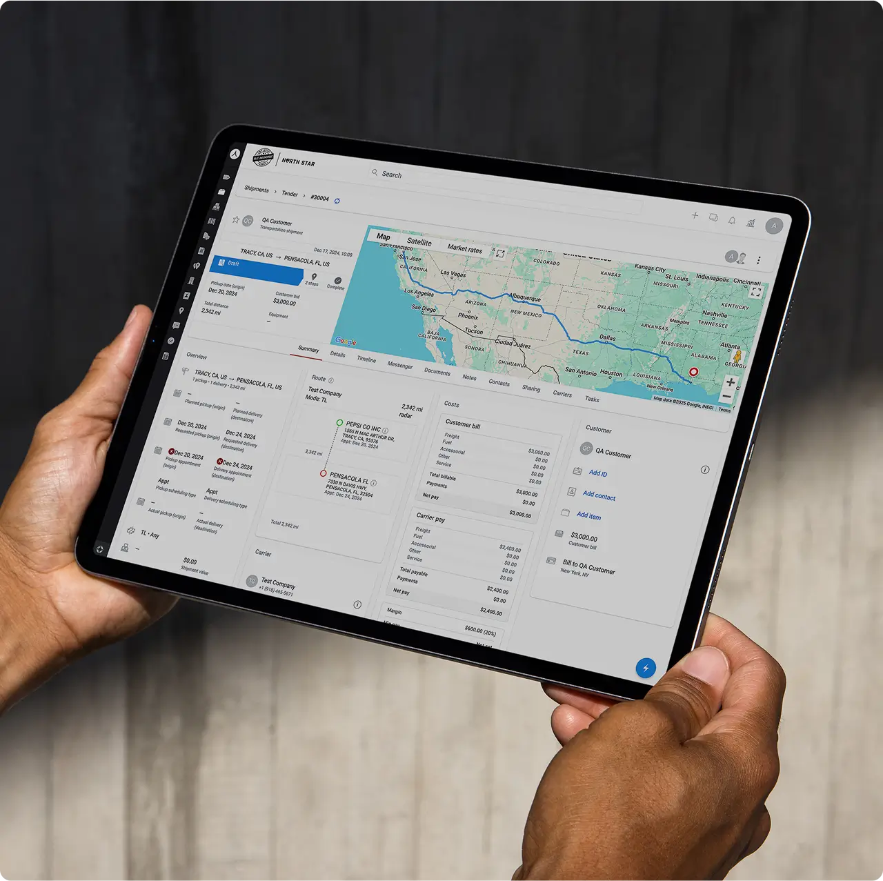 A person holds a tablet displaying a logistics management app with a route map, shipment details, and delivery information on the screen.